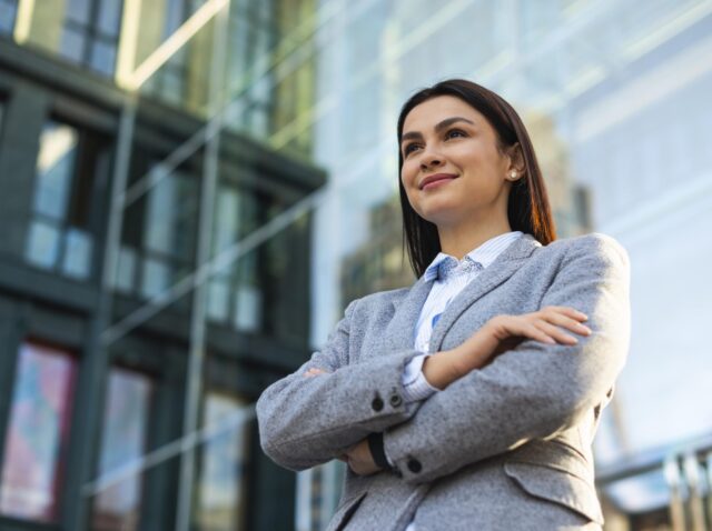 low-angle-businesswoman-posing-with-arms-crossed-city